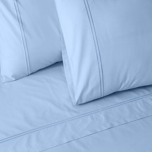 Close-up of mirage colour luxury embroidered bedding with two pillows on a matching bed sheet.