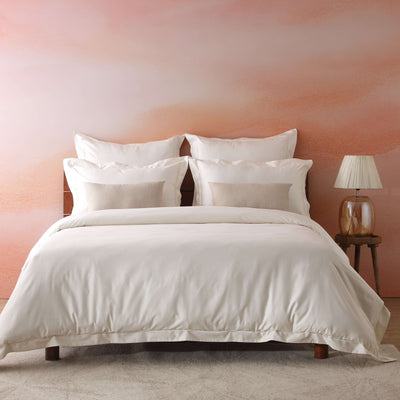 Full bed front view of 750 TC GOTS certified organic cotton duvet cover set in ivory with matching pillowcases on styled bed against pink wall and wooden headboard, Whites of London NZ 