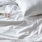 White bedding set with floral embroidery and a pillow on a plain background