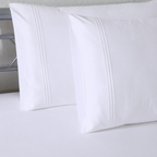 Close up of two Oxford pillowcases showing triple cord embroidery detail on headboard: 1250 TC GOTS certified Organic Cotton Sheet Set as well as Organic Cotton Fitted Sheet white pillowcases close up Whites of London. 