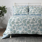 Left angle shot of Jacobean Windflower Percale Reversible Quilt Set folded on bed with reversible pattern visible, Whites of London
