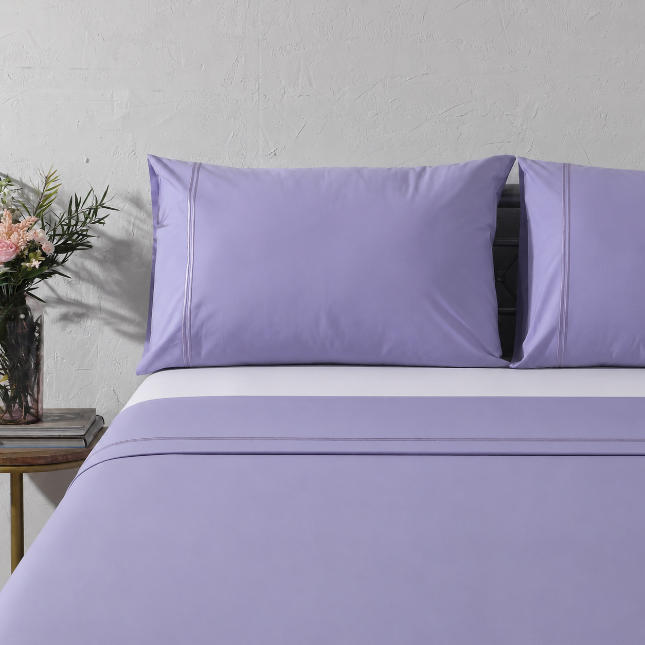 Full bed angled shot with Lavender Mist bedding, flowers and side table: 250TC GOTS certified Organic Cotton Coloured Sheet Set Lavender Mist embroidered full bed styling Whites of London New Zealand and Fitted sheet