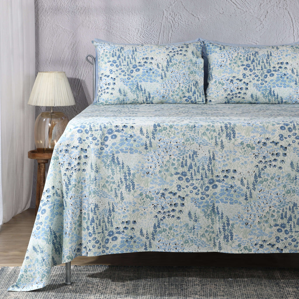Full bed lifestyle shot with lamp and curtains: Windflower 250 TC percale GOTS certified organic cotton percale printed sheet set blue floral full bed styled Whites of London NZ