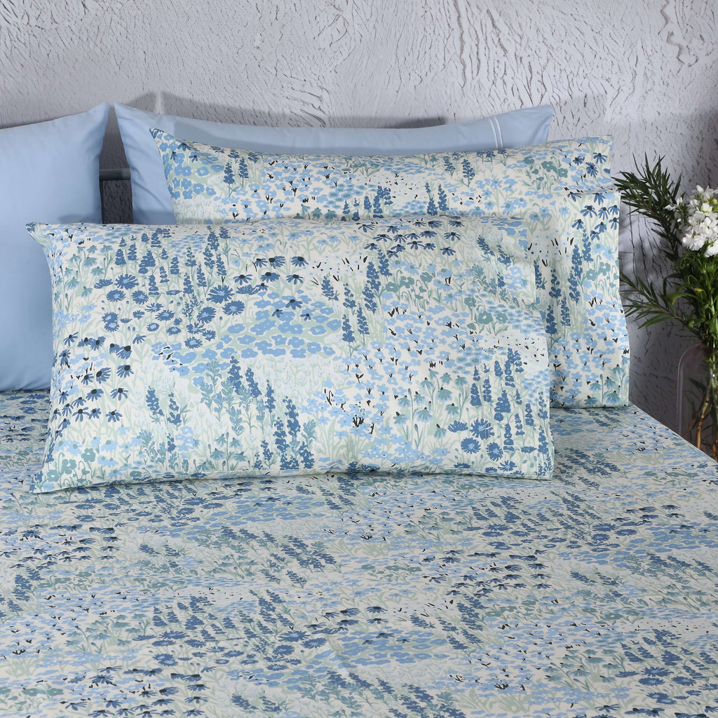 Close-up of Windflower blue floral pillowcases on bed, part of 250TC GOTS certified organic cotton percale printed sheet set