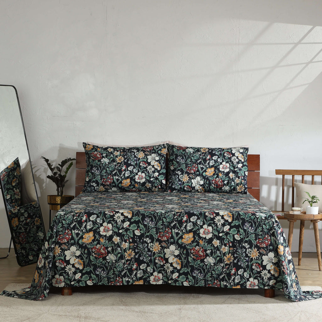 Front view of Adriana Black 250TC GOTS certified organic cotton percale printed sheet set displayed on a bed, black floral design with ivory, ochre, sage, and crimson accents