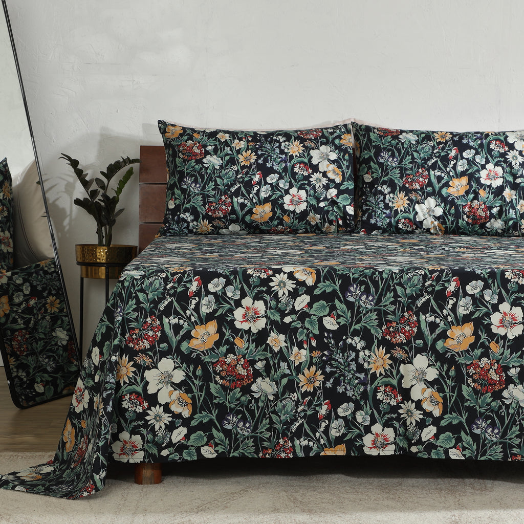 Left side view of Adriana Black 250TC GOTS certified organic cotton percale printed sheet set on bed, highlighting black floral print with ivory, ochre, sage, and crimson flowers