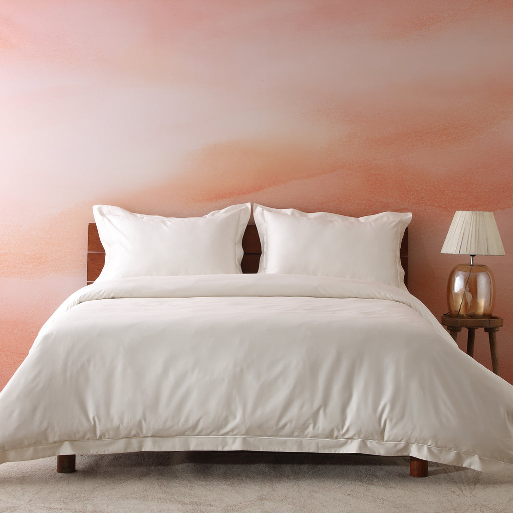 Ivory 750TC GOTS certified organic cotton pillowcases arranged on bed with matching duvet, showing embroidery