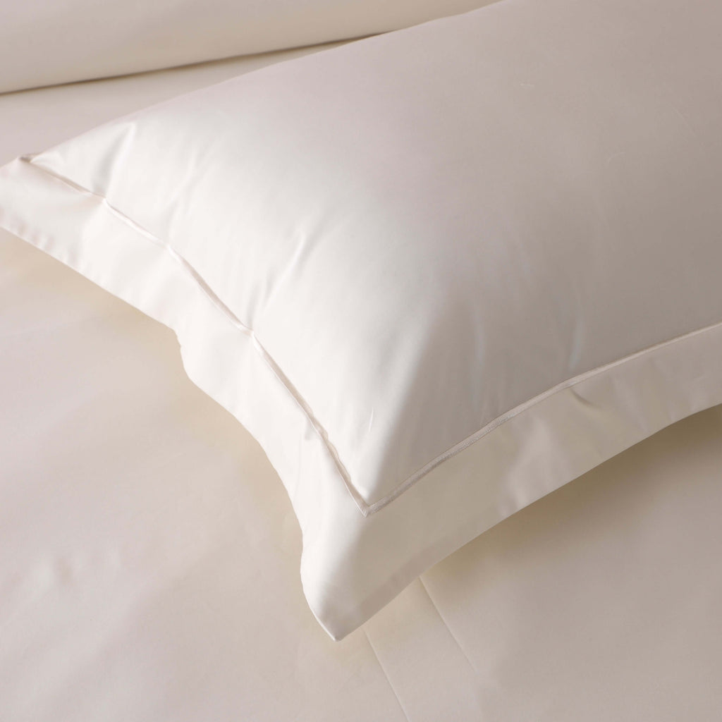 Overhead close-up of four ivory 750TC GOTS certified organic cotton pillowcases highlighting embroidery detail