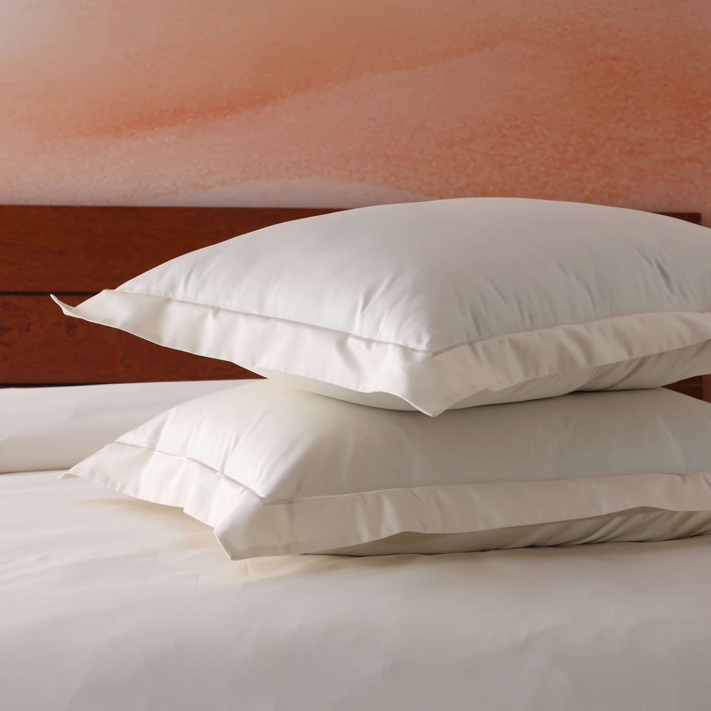 Two ivory 750TC GOTS certified organic cotton pillowcases stacked showing embroidered detail