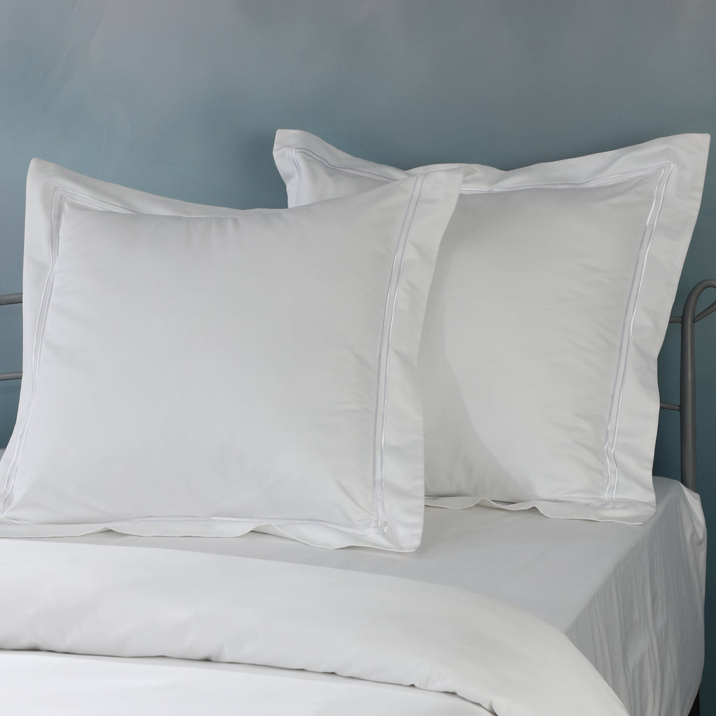 Two white euro GOTS certified organic cotton pillowcase on bed showing embroidered detail in 1250TC 