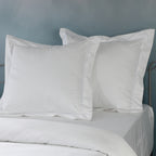 Two white euro GOTS certified organic cotton pillowcase on bed showing embroidered detail in 1250TC 