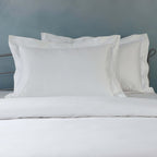 Close-up of 1250TC organic cotton pillowcases in white with oxford style and embroidered detail on styled bed