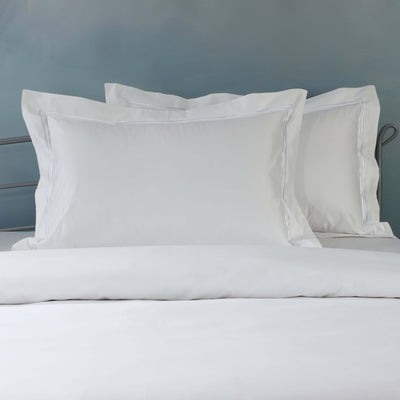 Close-up of 1250TC organic cotton pillowcases in white with oxford style and embroidered detail on styled bed