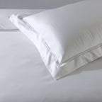 Extreme close-up of single white pillowcase corner showing cord embroidery, part of 1250TC  GOTS certified organic cotton pillowcases