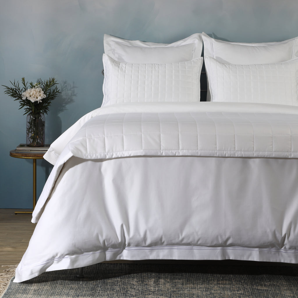 Angled close-up of white bedspread and pillowcases from Bamboo Cotton Bedspread Set showing quilted square pattern with side table, Whites of London NZ