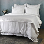 White bedspread layered over white duvet angled shot with flowers: White bamboo cotton bedspread set layered luxury bedroom styling flowers Whites of London