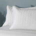 Close-up of two white pillowcases from Bamboo Cotton Bedspread Set showing quilted square stitching detail on bed, Whites of London NZ