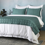 Angled shot of teal bedspread over white duvet with pillowcases: Teal bamboo cotton bedspread set quilted square design layered white duvet Whites of London