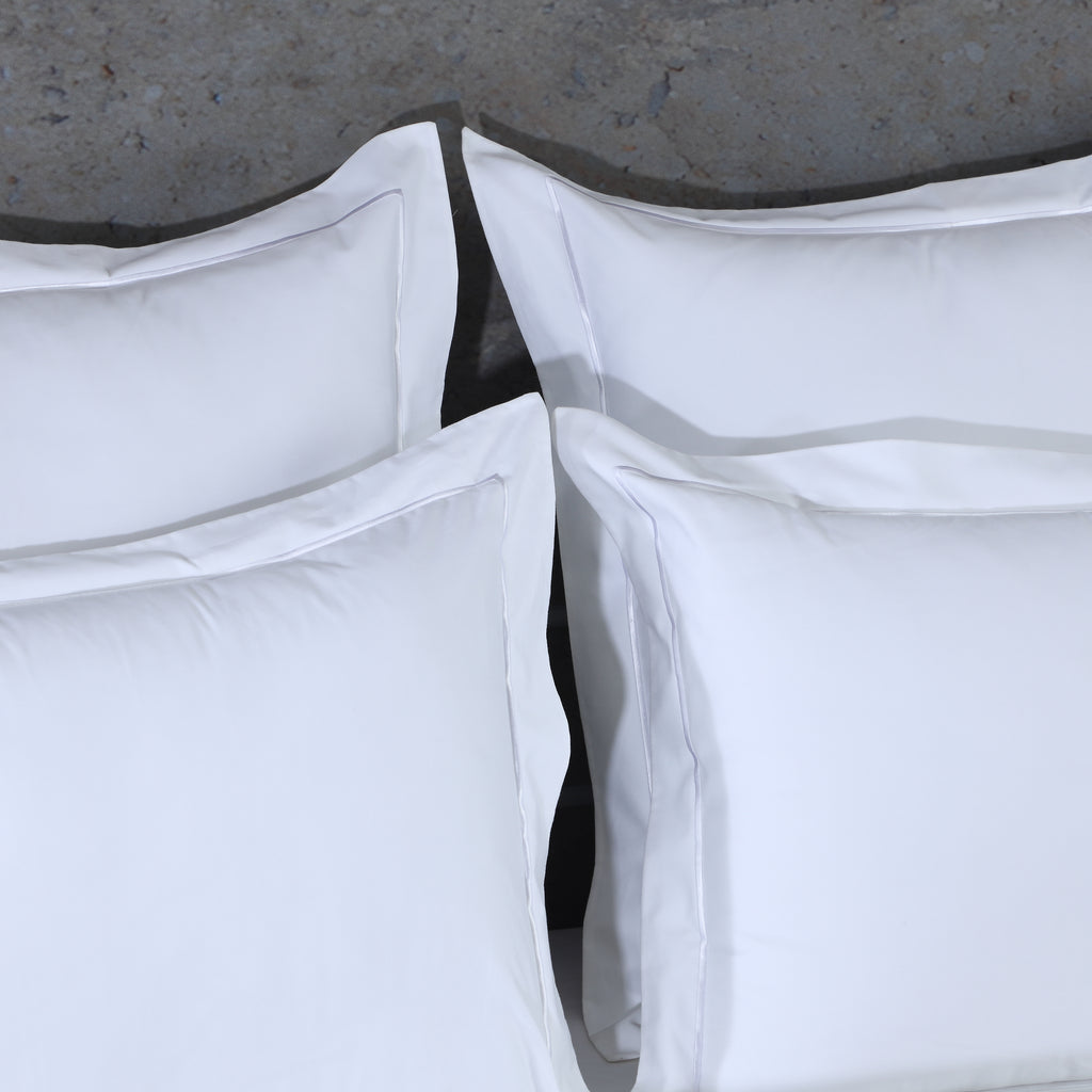 Close-up of four 750TC euro GOTS certified organic cotton pillowcases highlighting cord embroidery and flange detail