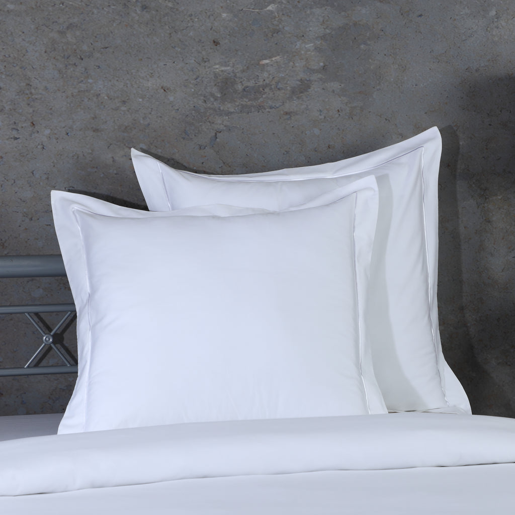 Two white euro pillowcases propped against metal headboard, part of 750TC GOTS certified organic cotton pillowcases