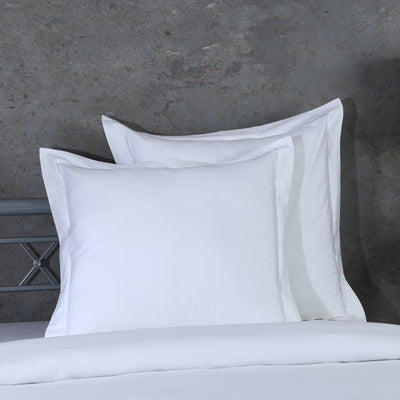 Two white euro pillowcases propped against metal headboard, part of 750TC GOTS certified organic cotton pillowcases