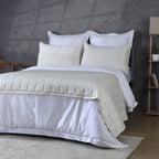 Side angled shot ivory bedspread over white duvet with shelf: Ivory bamboo cotton quilted bedspread set side angle white duvet concrete wall Whites of London