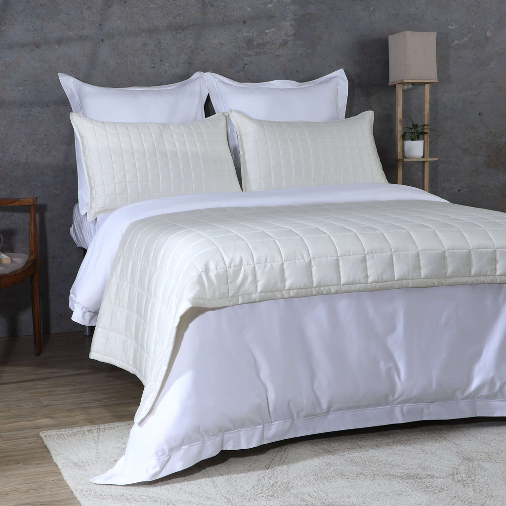 Angled full bed shot ivory bedspread over white duvet with lamp: Ivory bamboo cotton bedspread set angled full bed white duvet layered styling Whites of London
