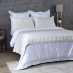 Angled full bed shot ivory bedspread over white duvet with lamp: Ivory bamboo cotton bedspread set angled full bed white duvet layered styling Whites of London