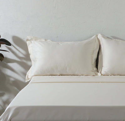 Angled bed shot with pillowcases and flat sheet: 750TC GOTS certified Organic Cotton Sheet Set Embroidered angled bed ivory pillowcases flat sheet plant shadow Whites of London 